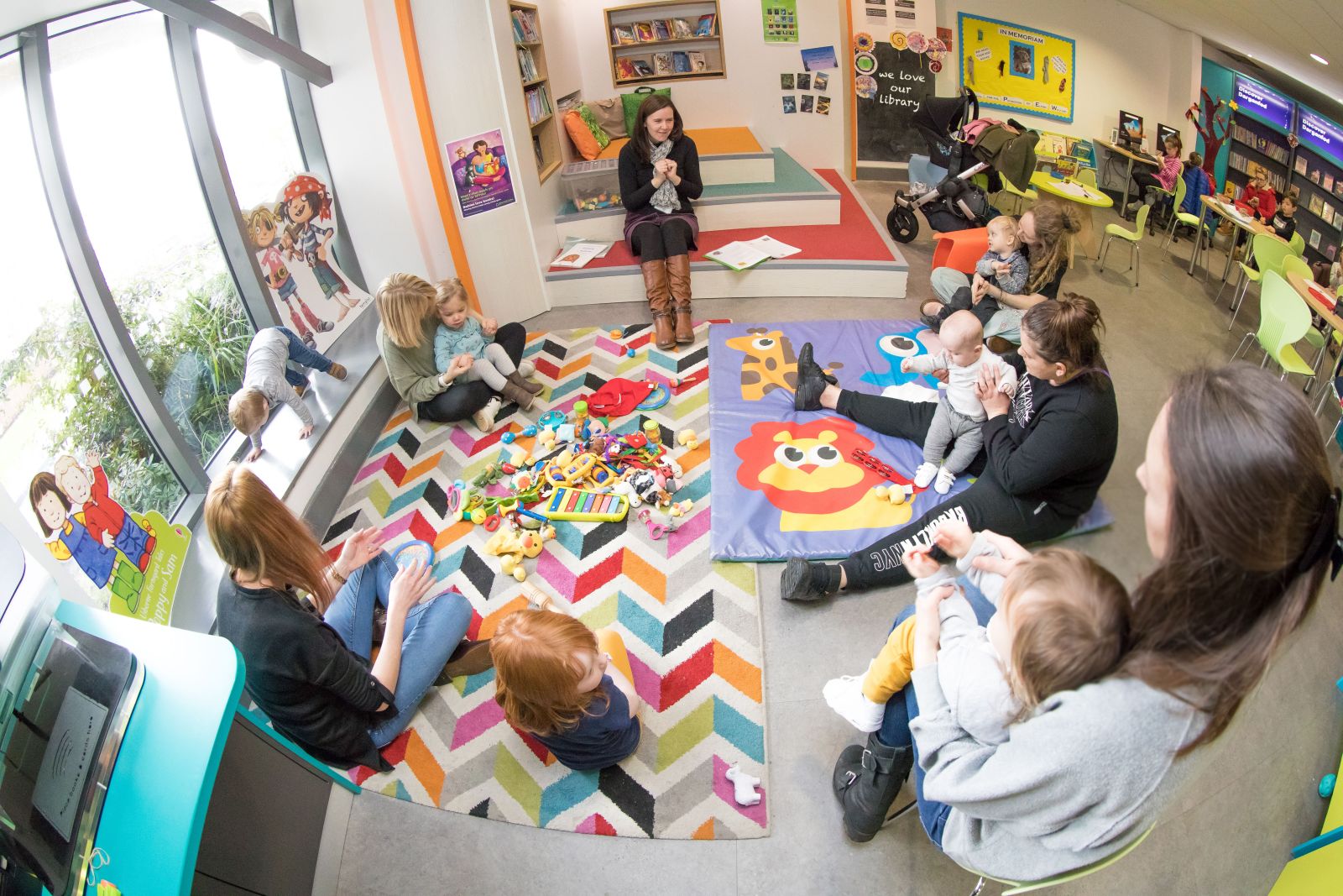 Photograph of young children and their parents enjoying a Bounce and Rhyme session at a library.